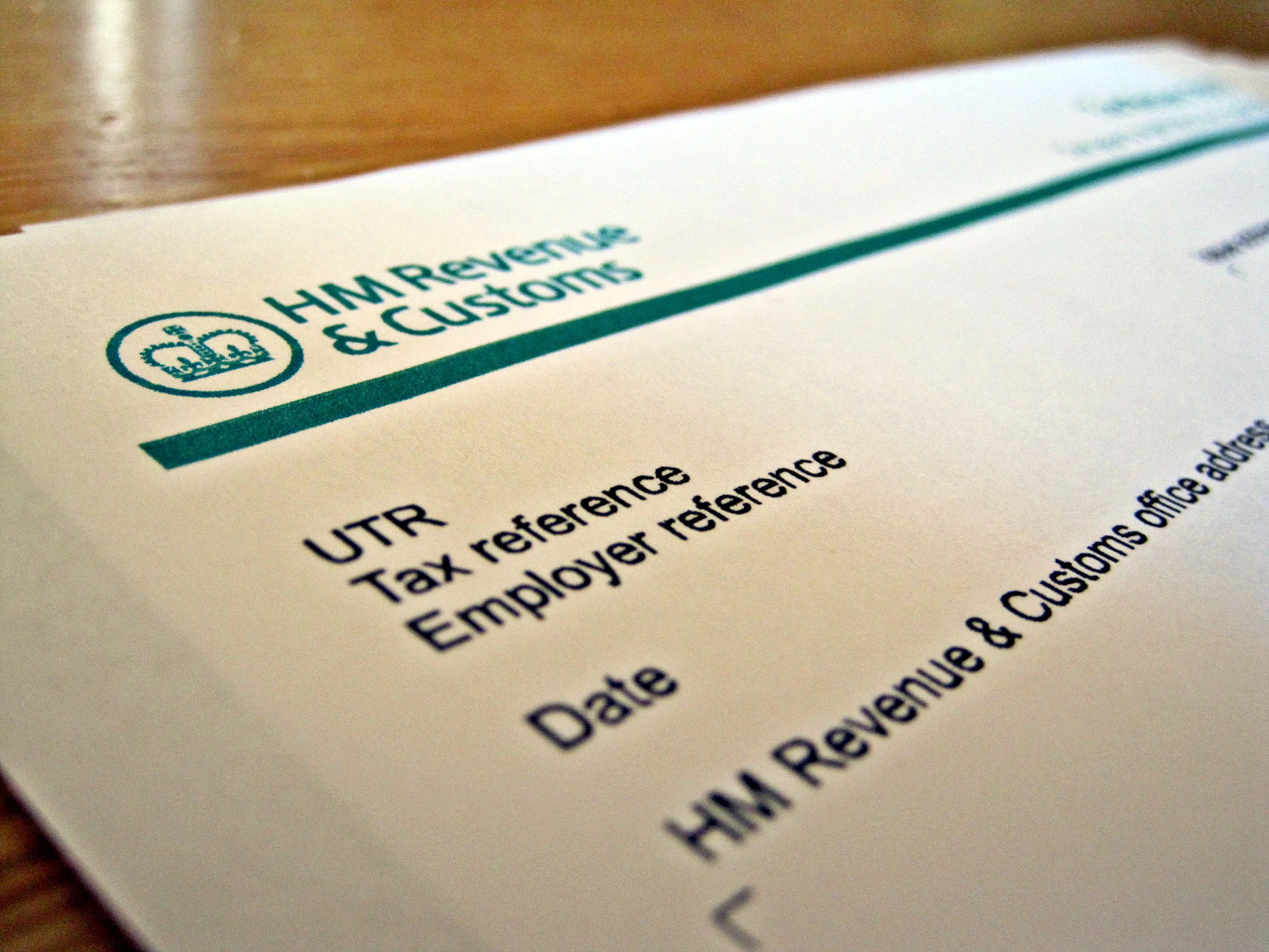 Documento da HM Revenue & Customs, o fisco britânico, pousado numa mesa de madeira, com os campos de referência fiscal e de referência do empregador.